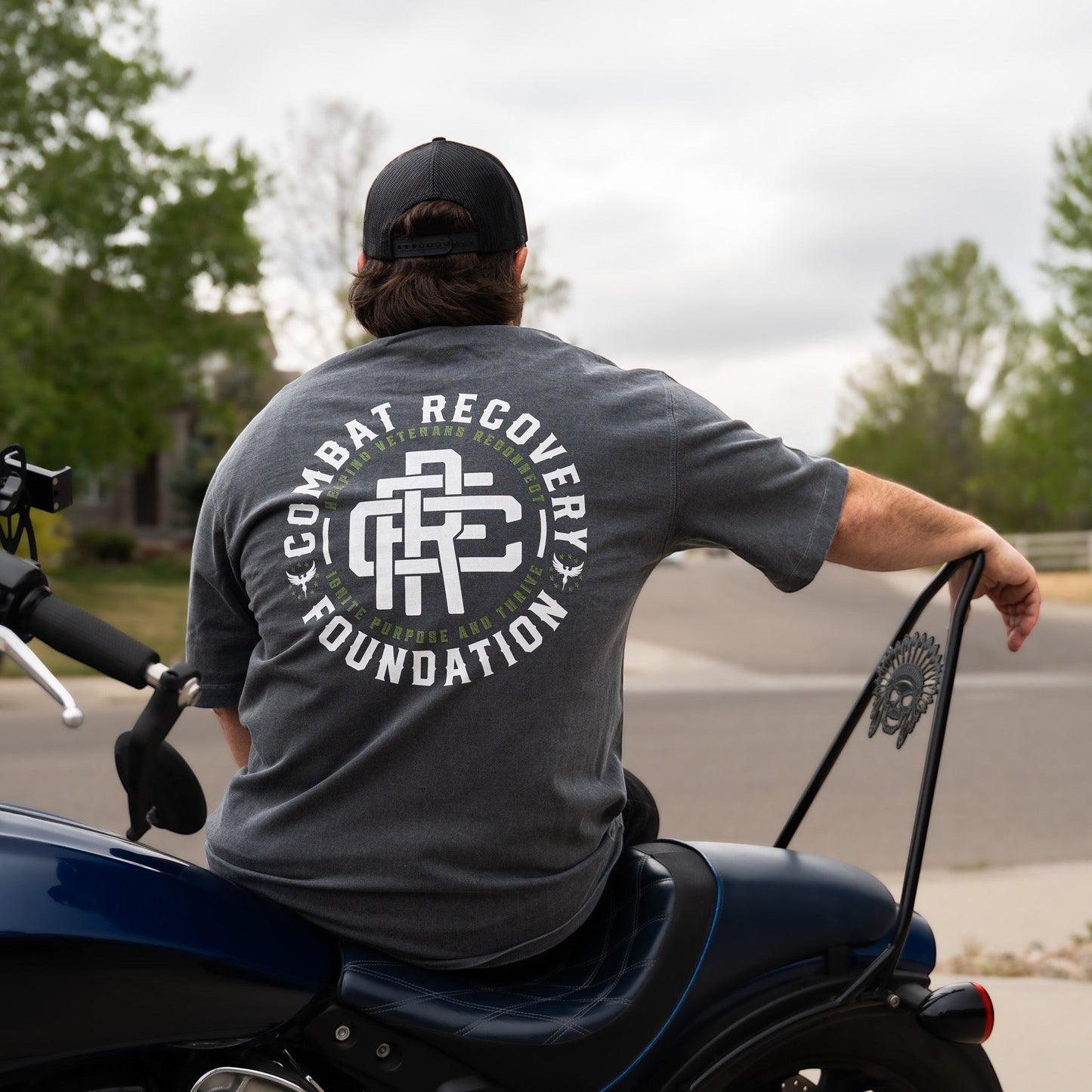 Person wearing a 'Combat Recovery Foundation' t-shirt on a motorcycle.